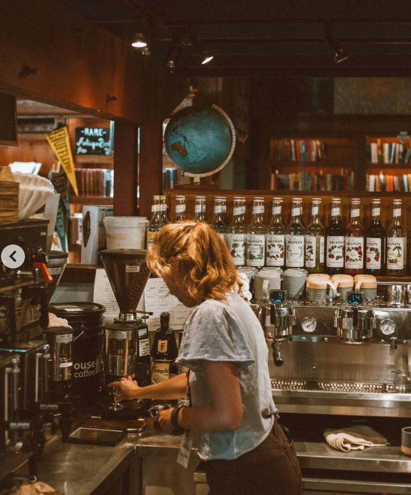 The coffee bar at Off The Beaten Path. A barista makes coffee at the espresso machine. 