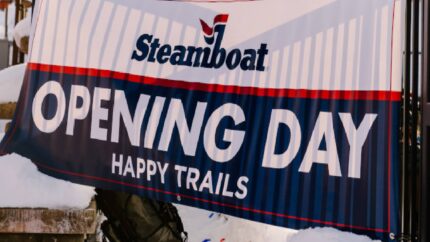 Sign at Steamboat Resort stating "Opening Day" in large white letters, below are the words "Happy Trails"