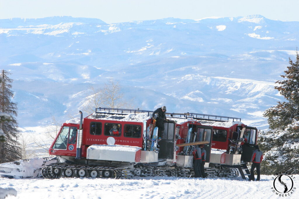 A red Snowcat perched on top of the mountain overlooking the town. 