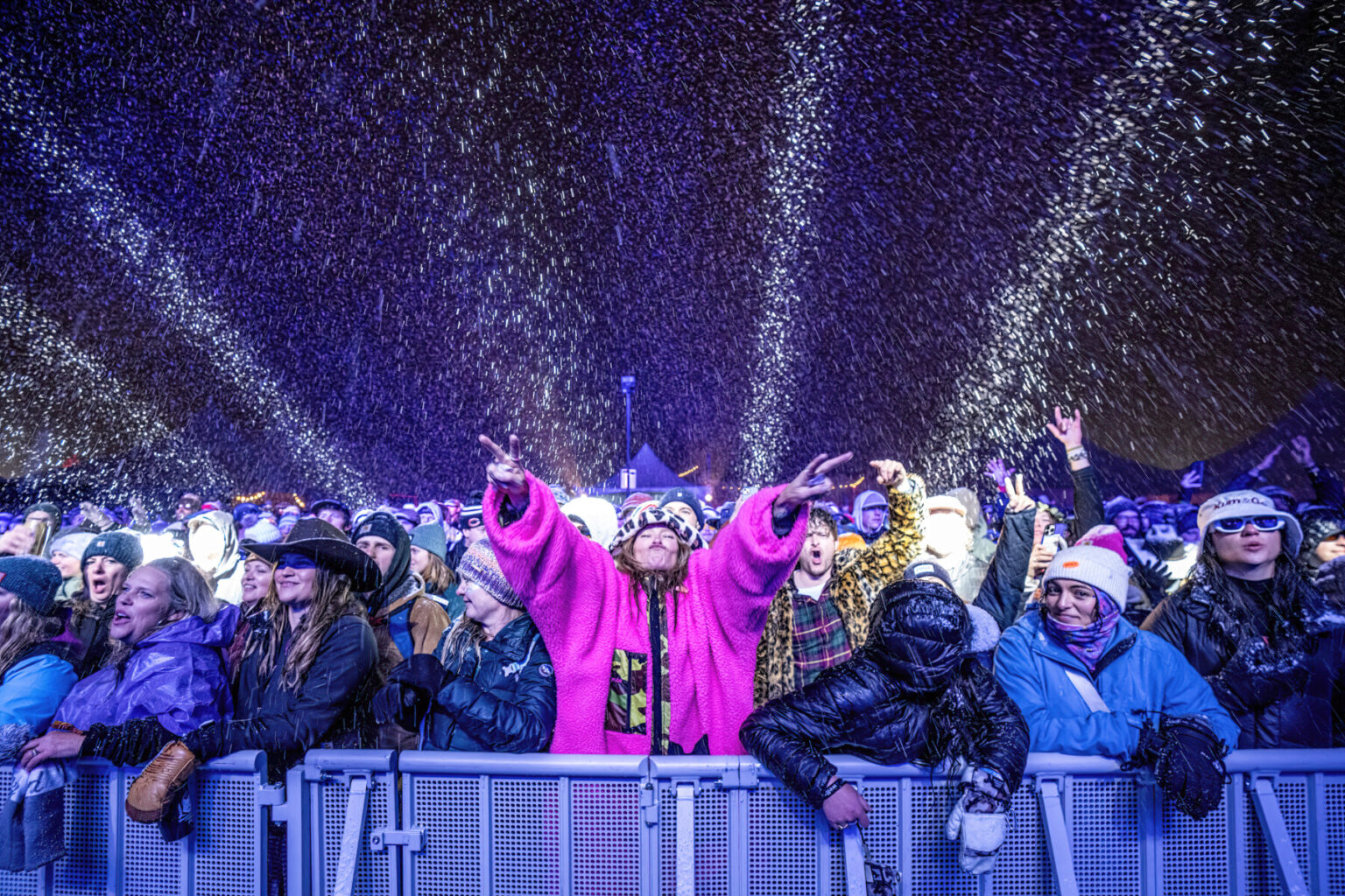 A crowd standing in the falling snow during the WinterWonderGrass Festival.