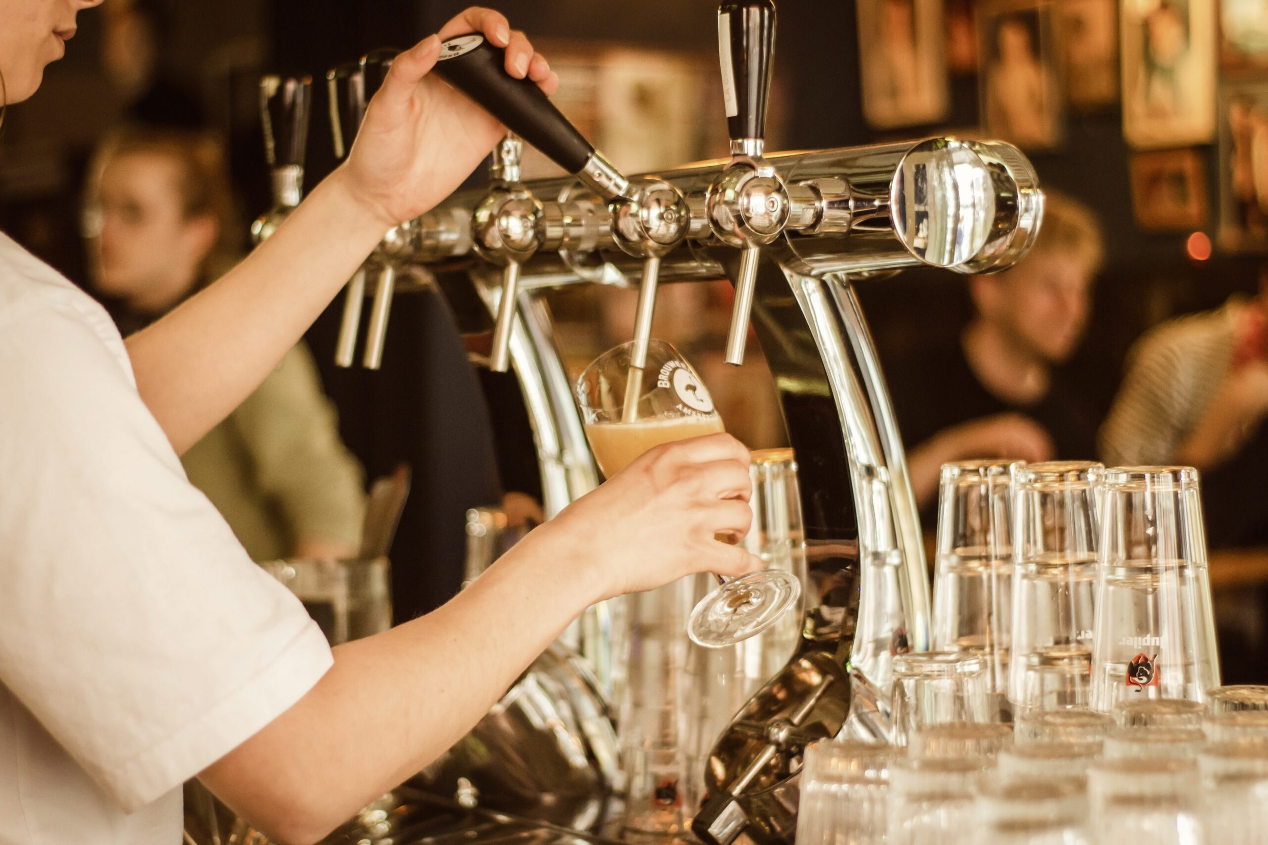 Women pouring draft beer into a glass at a bar.