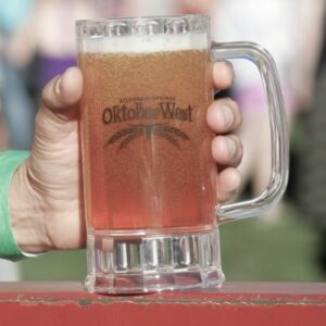 Hand holding a beer stein that has the word OktoberWest on it.