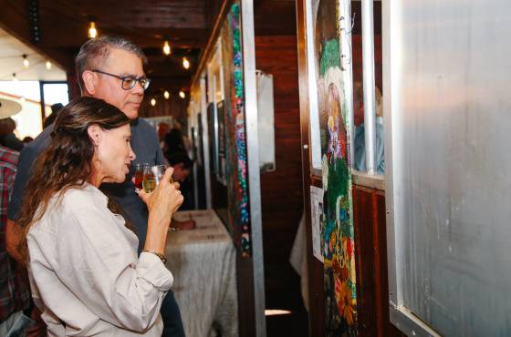Two attendees observe a vibrant, climate-themed art piece at the opening reception of Insight: Art for Climate Action in Steamboat Springs.