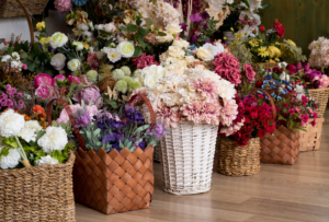 Colorful floral arrangements in woven baskets featuring pink roses, white dahlias, purple flowers, and seasonal greenery displayed at a luxury florist shop in Steamboat Springs.