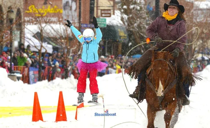 Child on skis being pulled by a woman on horseback
