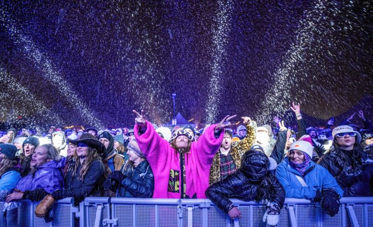 A crowd standing in the falling snow during the WinterWonderGrass Festival.