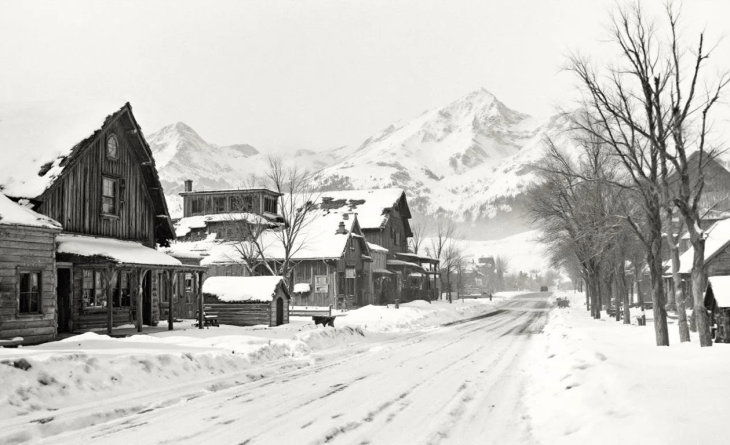 Historic snow-covered street in Steamboat Springs with old wooden buildings and mountains in the background.